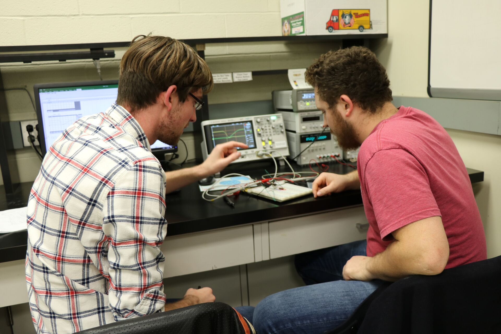 Two students working together and sitting in front of a computer.