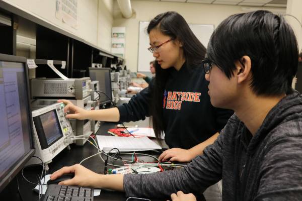 Two students examining a computer.