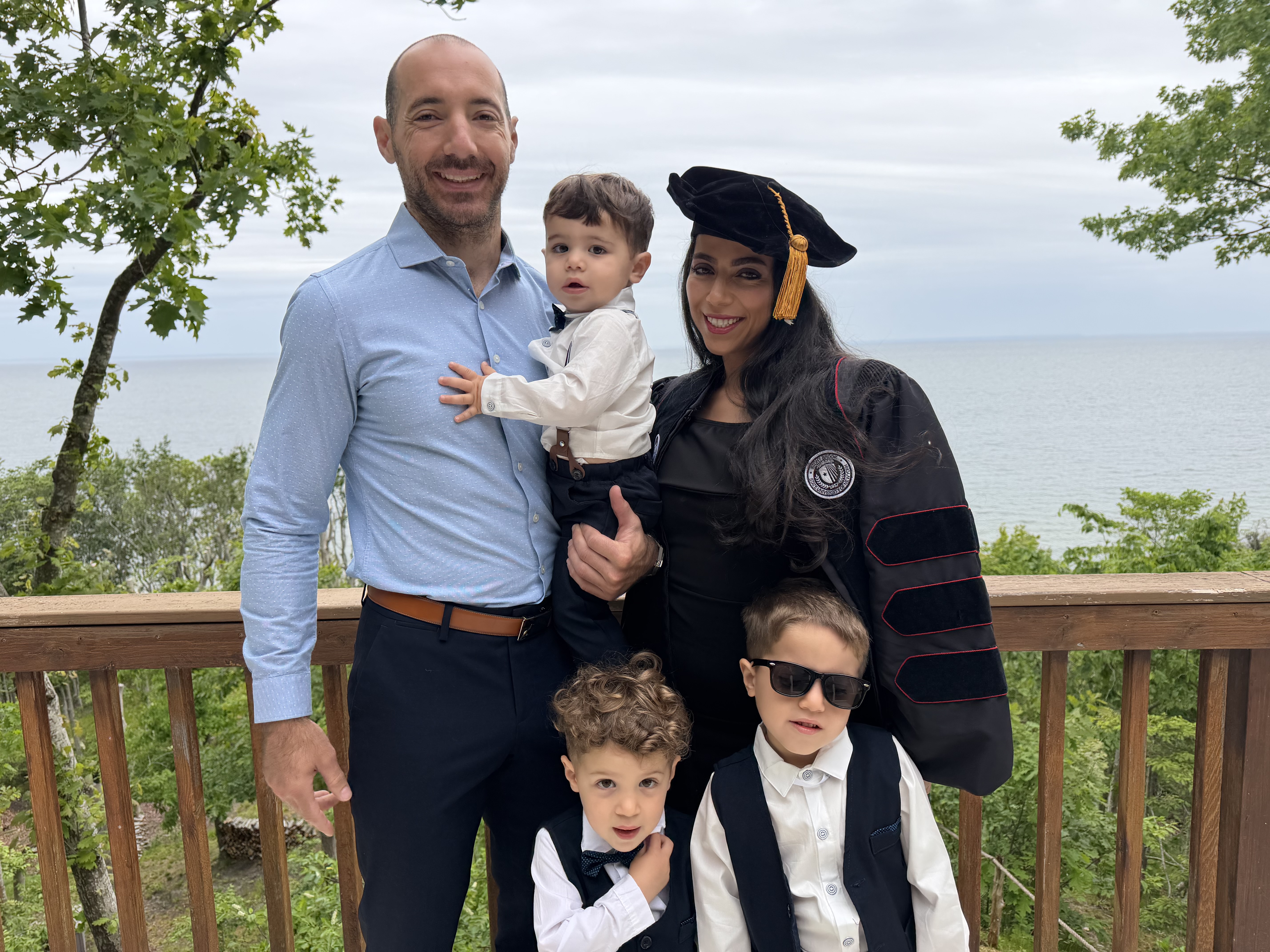 Zahraa, wearing regalia, posing with her spouse and children.