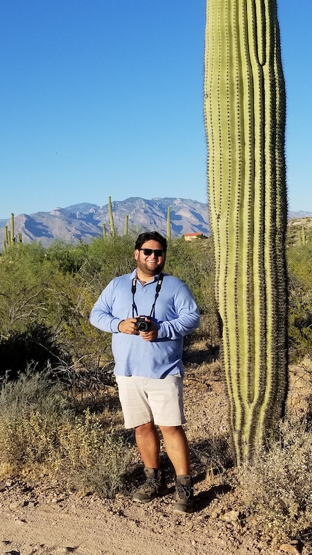 Danny Ventura standing next to a giant cactus.