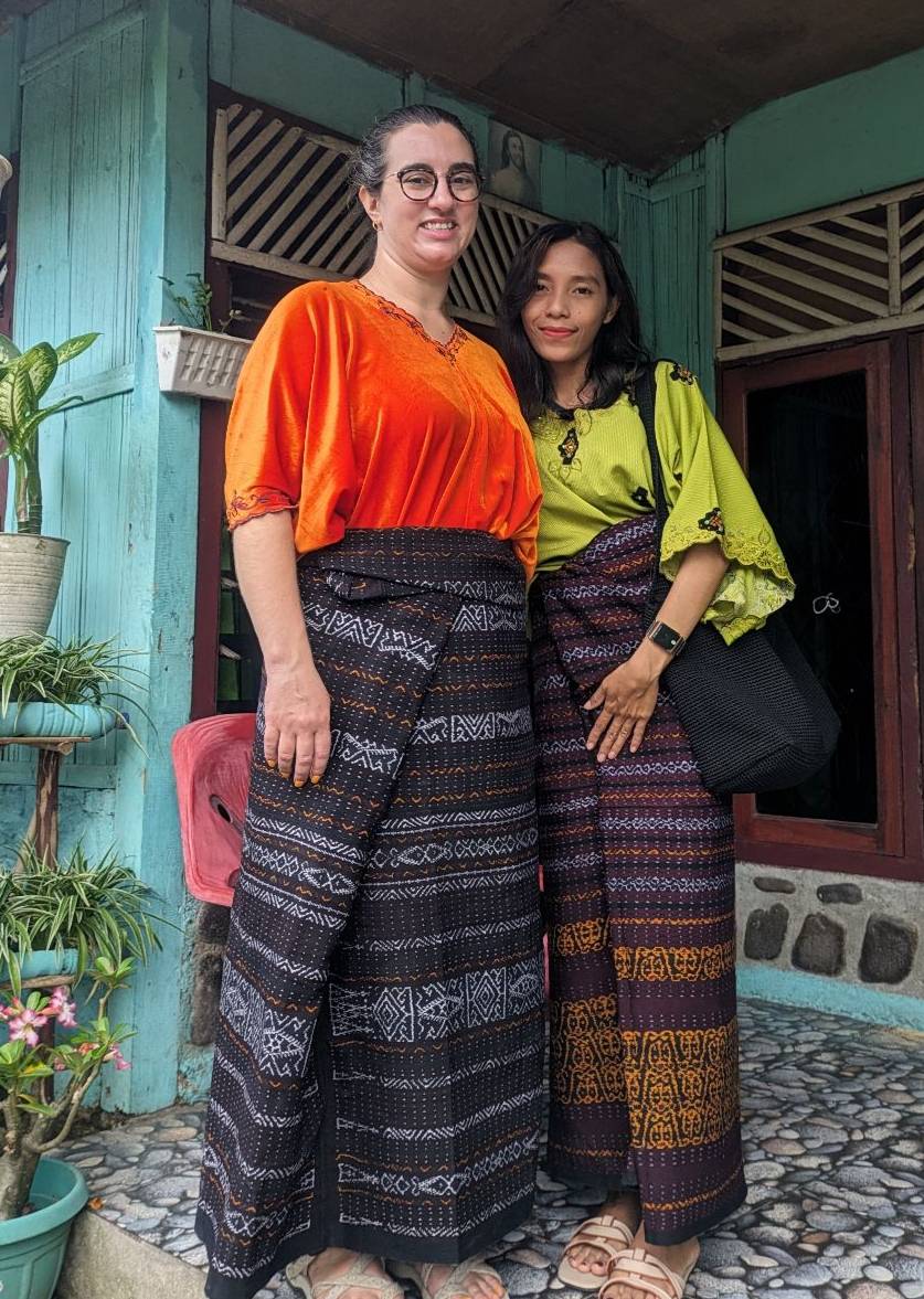 Two women in typical Indonesian dress in front of a house