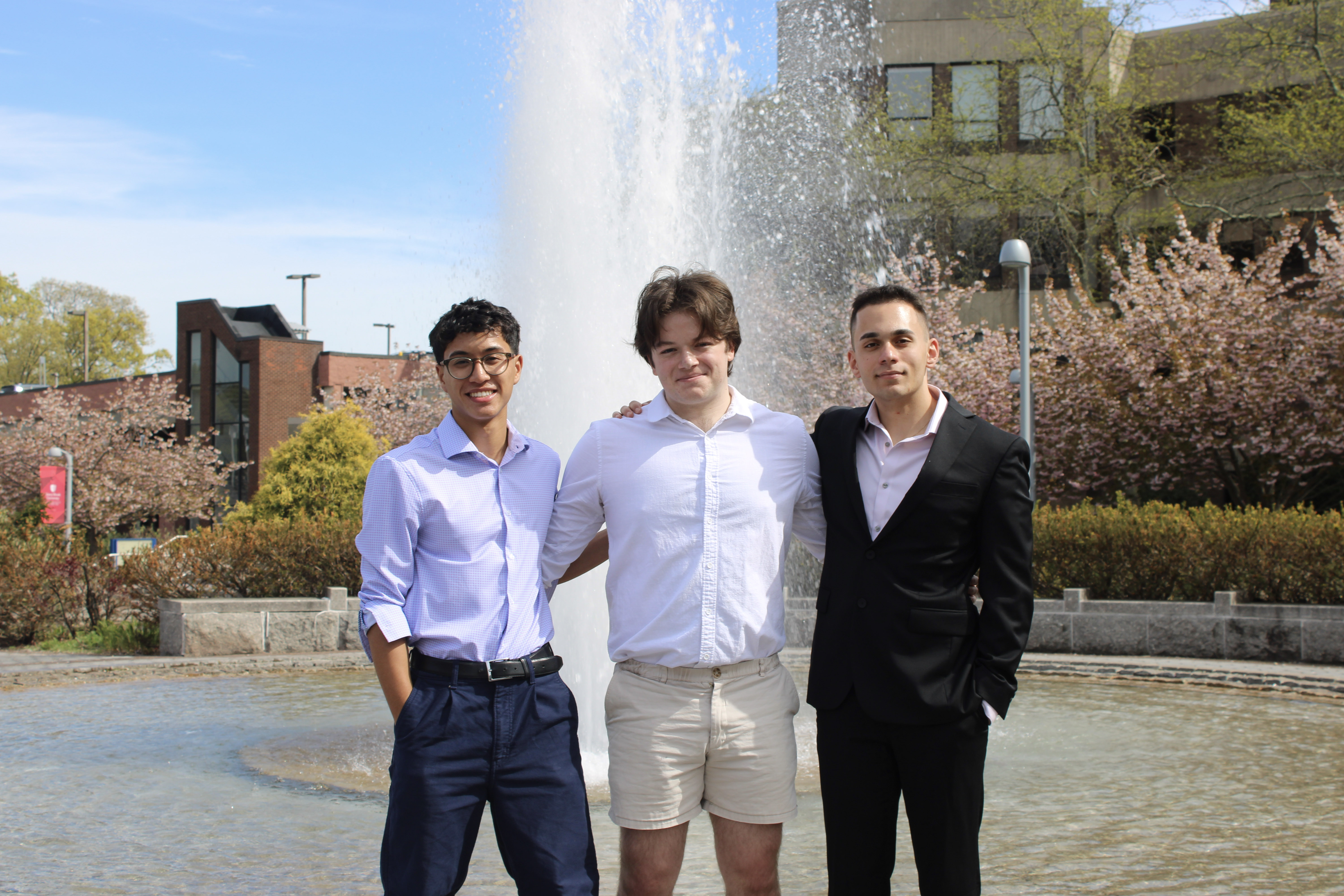 Three college students in front of a fountain