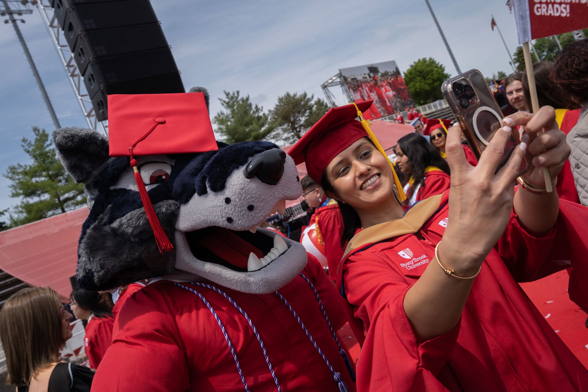Student taking a selfie with Wolfie at commencement