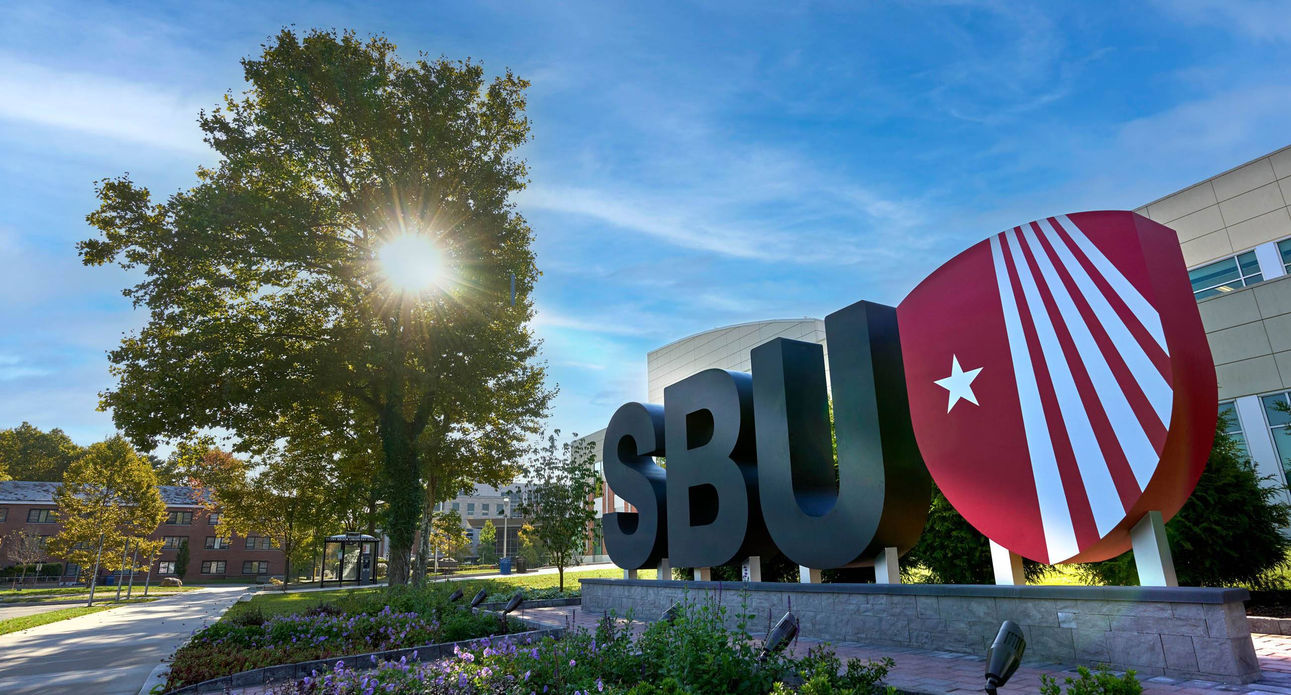 Large SBU letters with the Stony Brook shield on a sunny day.