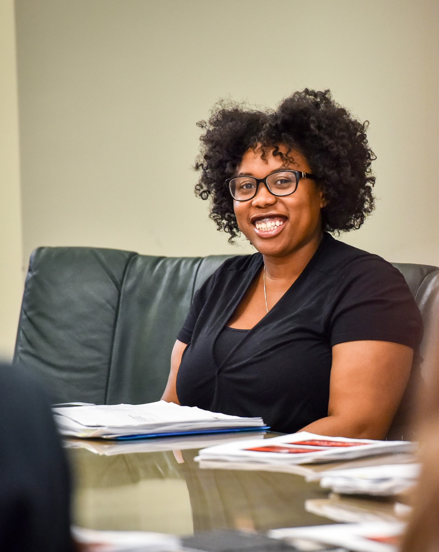 An HEA student grinning at the camera with a worksheet in front of her
