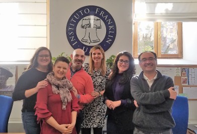 Group of six colleagues smiling together in front of an Instituto Franklin logo.