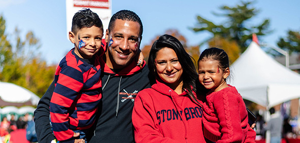 Alumni family on game day at stadium with kids