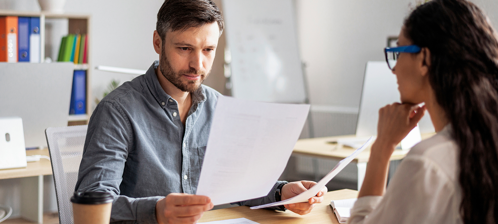 An HR director comparing two documents at a meeting with an employee
