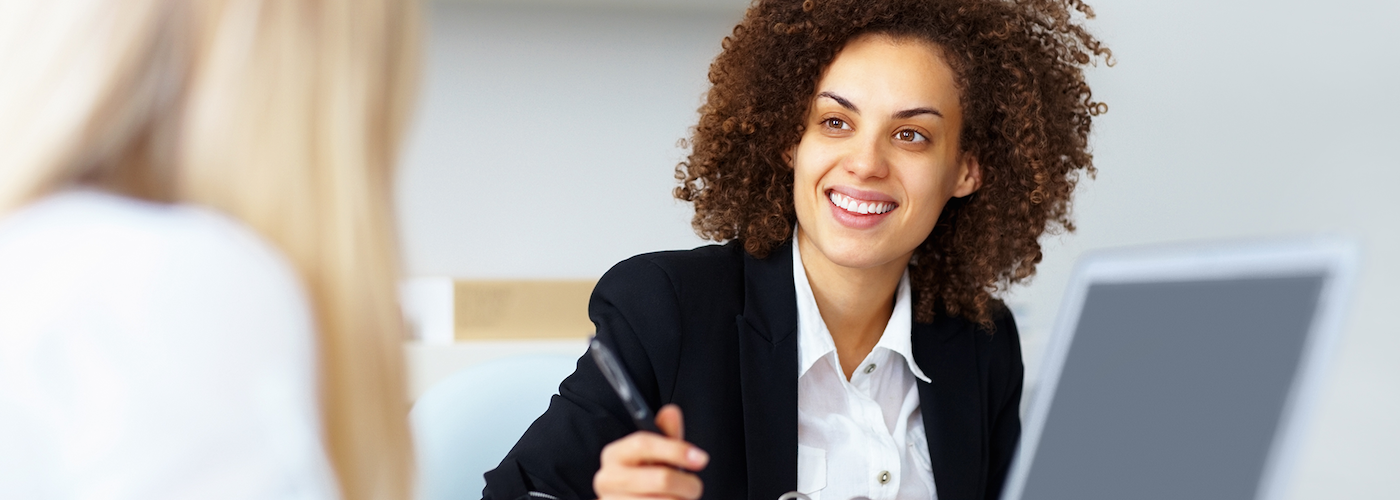 A woman interviewing someone while holding a pen