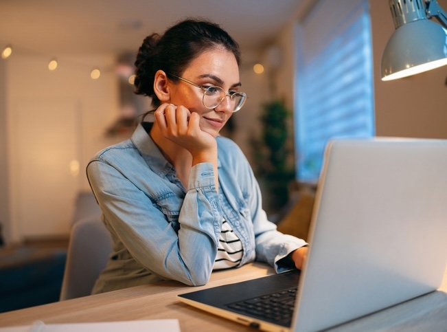 A woman on her laptop with a desk lamp beside her
