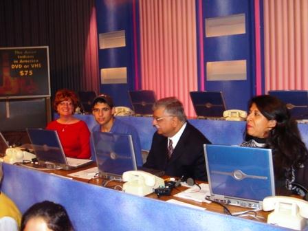 Four people sitting at a table with laptops
