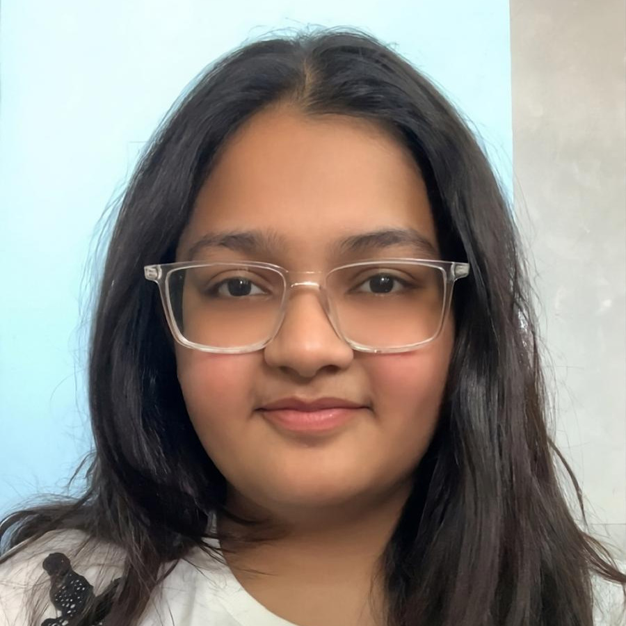 Girl with dark hair and glasses smiles with a presentation screen behind her