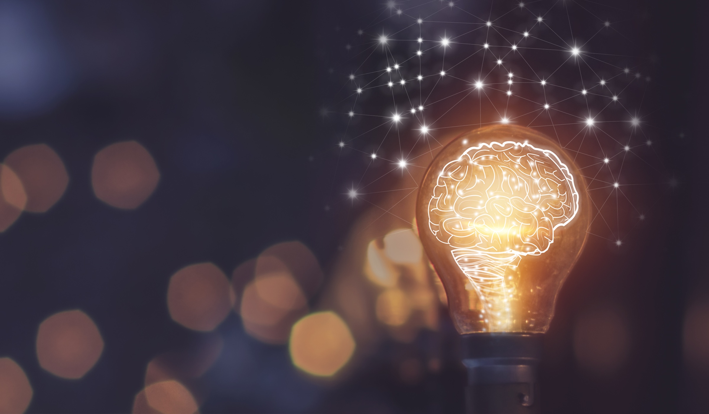 lightbulb illuminating orange light ro reveal human brain. Blurred background with particle effects