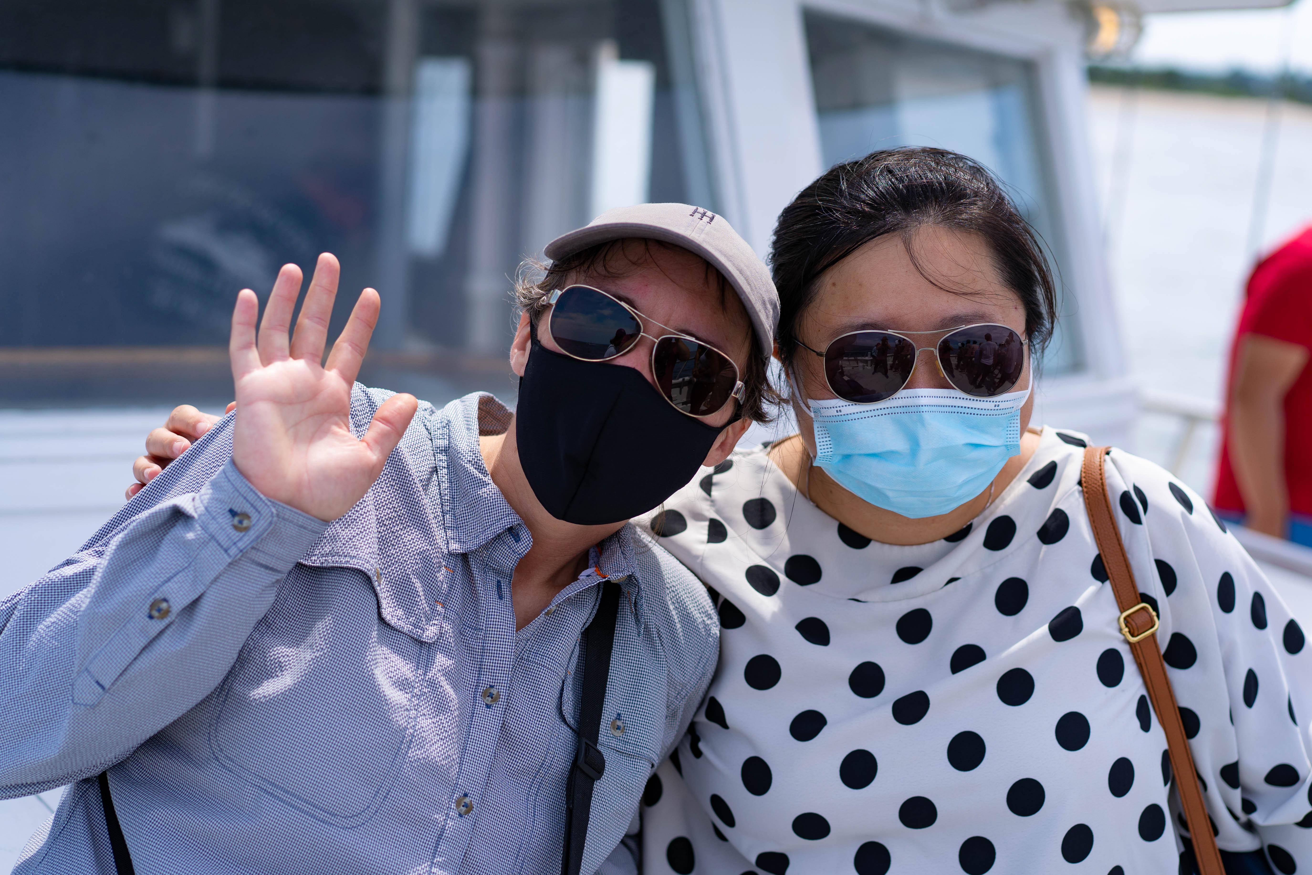 Two people wearing sunglasses and masks on a boat
