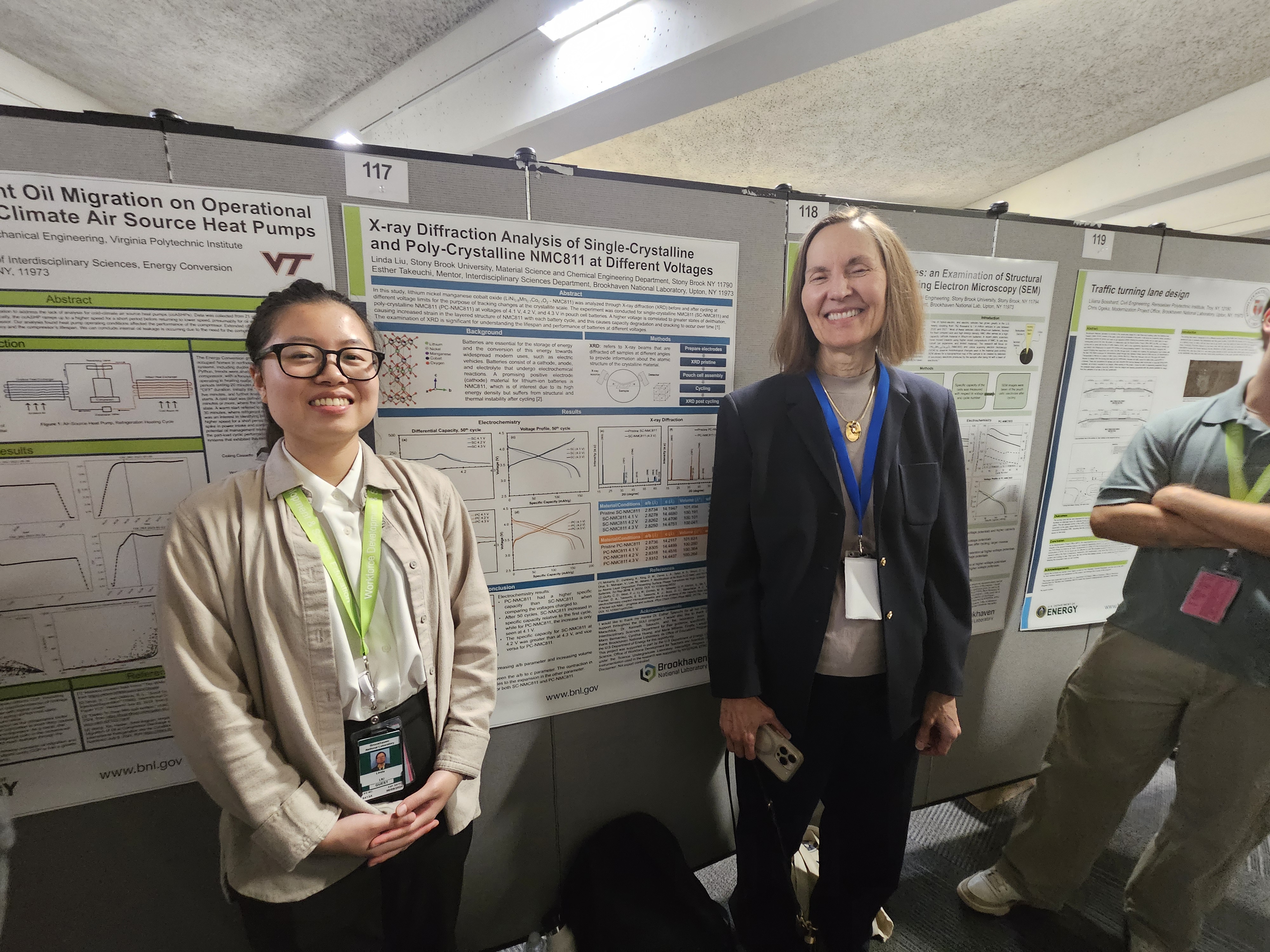 Two people smiling in front of a poster