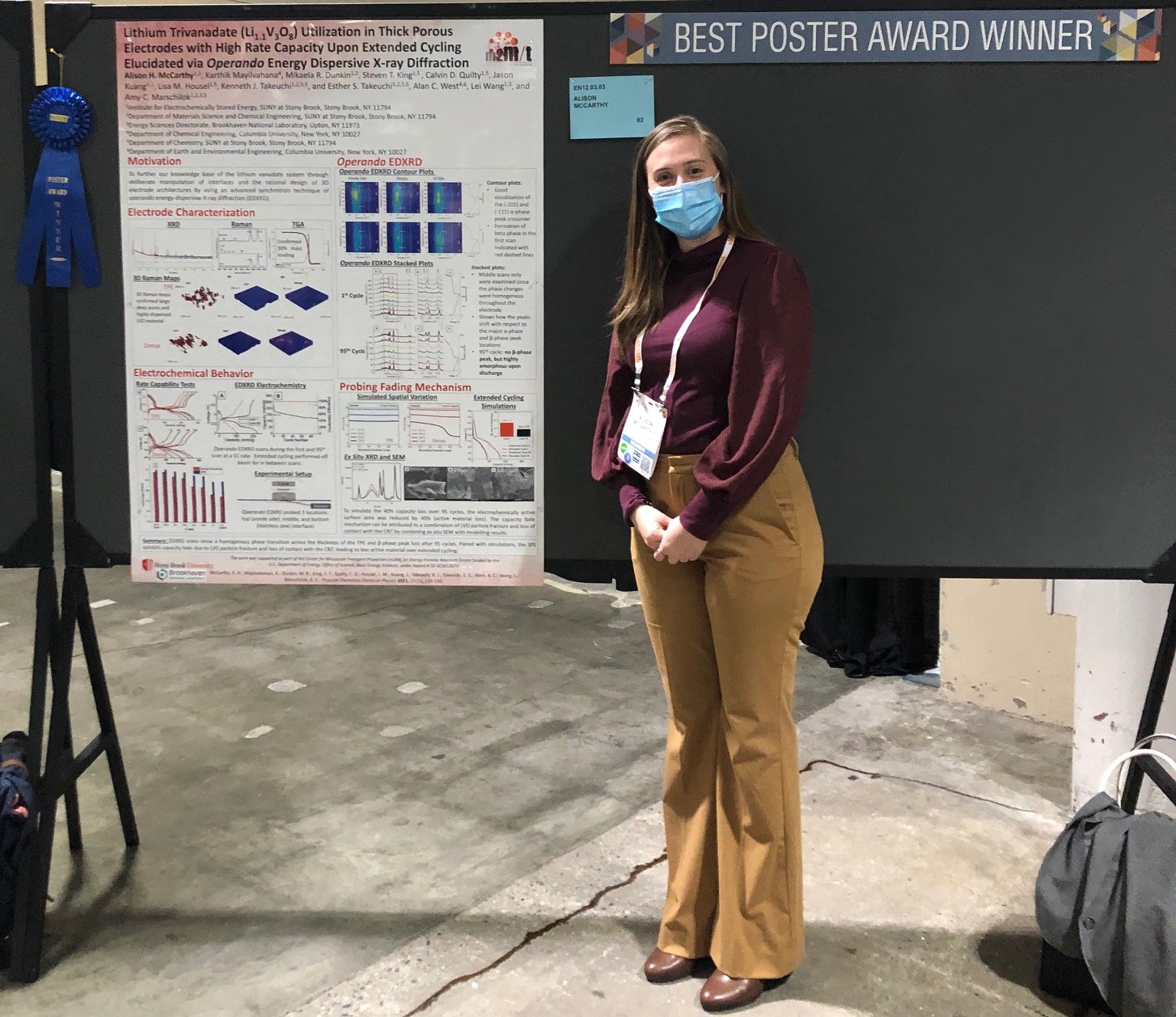 Student in front of a Best Poster Award Winner sign