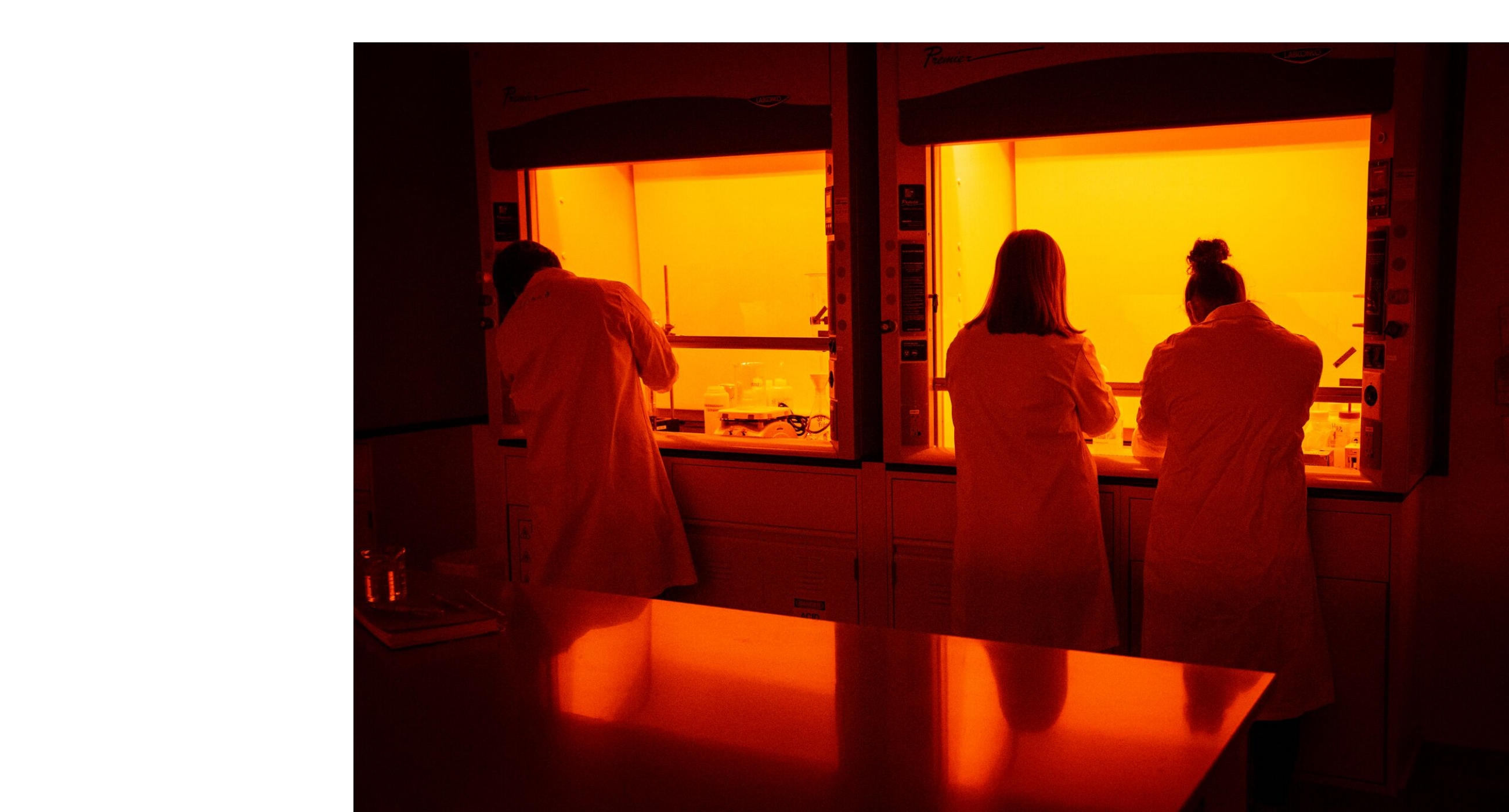 Researchers working in a laboratory with specialized equipment under orange lighting