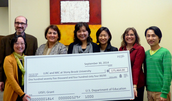 Seven faculty members holding a giant check