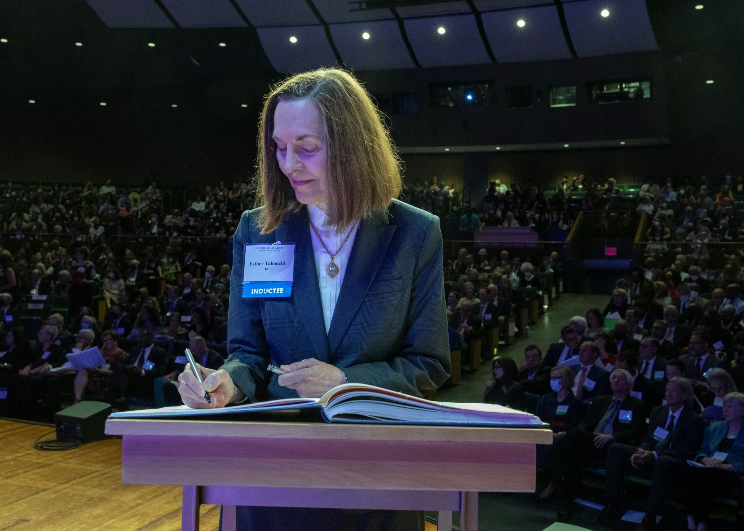 Dr. Esther Takeuchi signing a book on stage