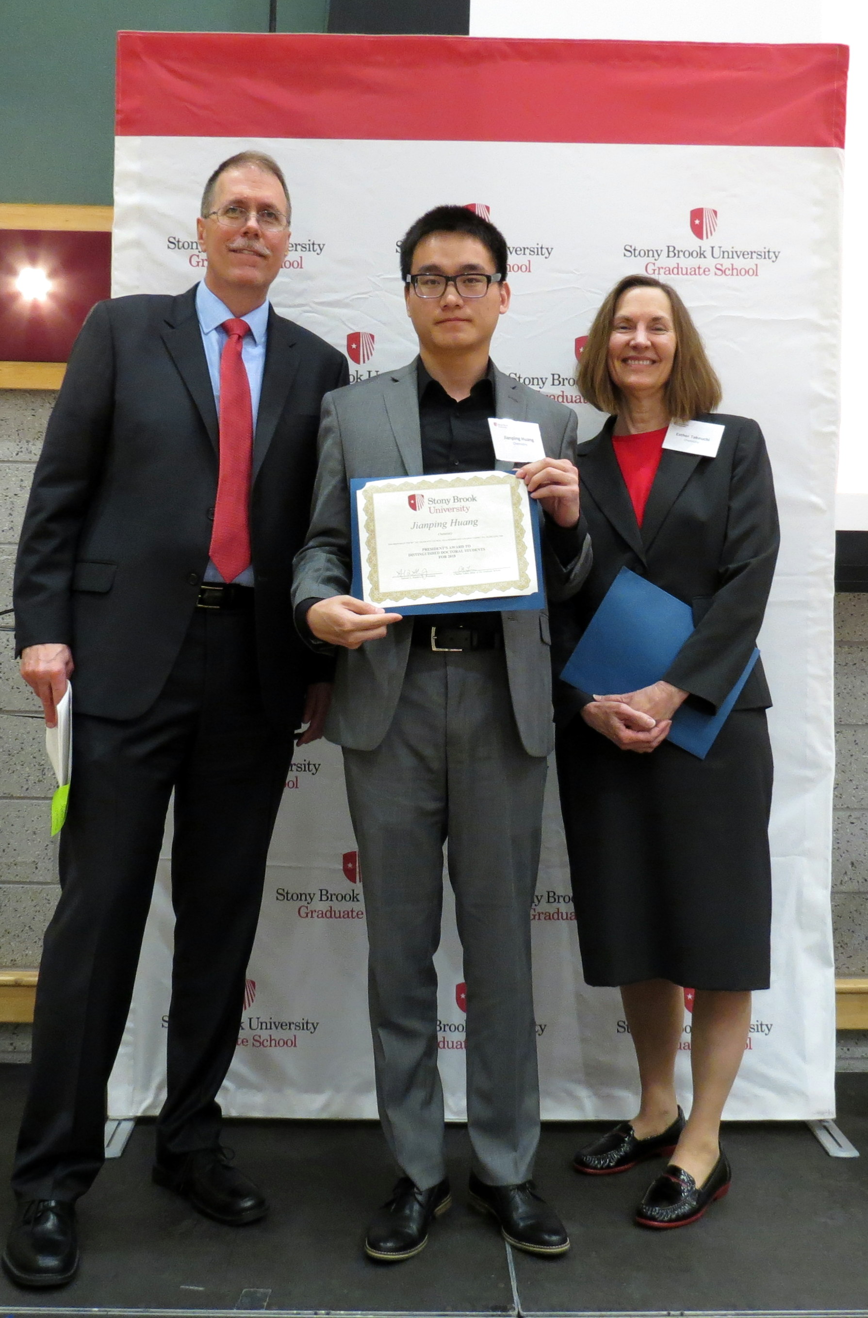 Three people smiling holding a certificate