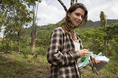 Student holding baggies and papers in the field