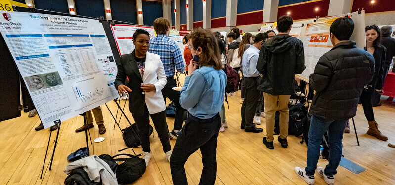 Students presenting and discussing research posters during a departmental research symposium