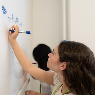 Samantha draws an equation with a blue marker on a whiteboard
