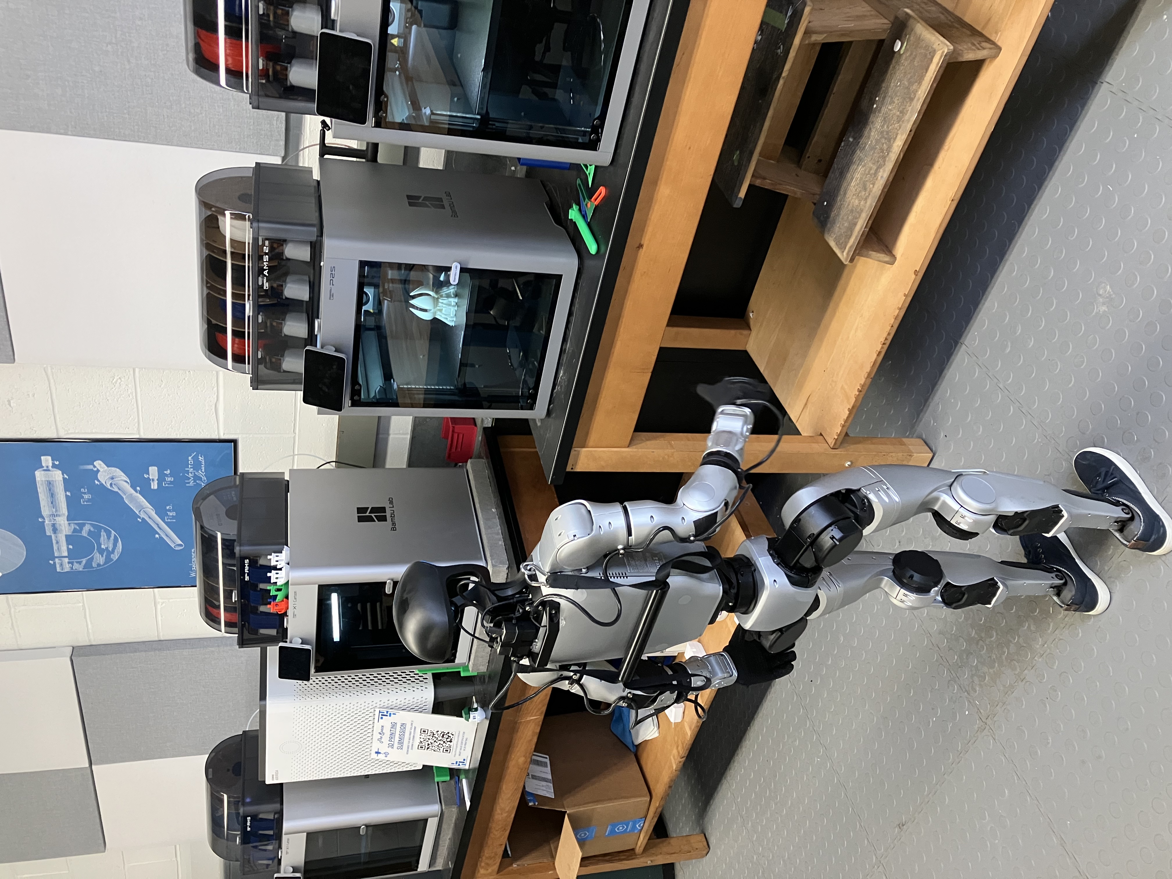 Robot waiting for 3-D printer to finish in maker space