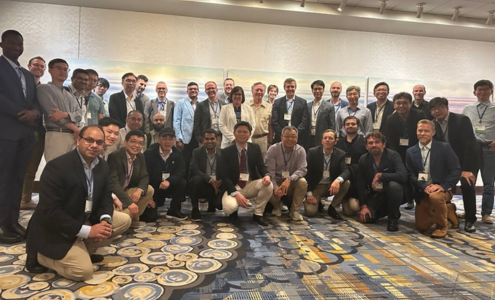 Group photo of the ASME Mechanisms and Robotics committee gathered indoors, with members standing and kneeling in several rows.