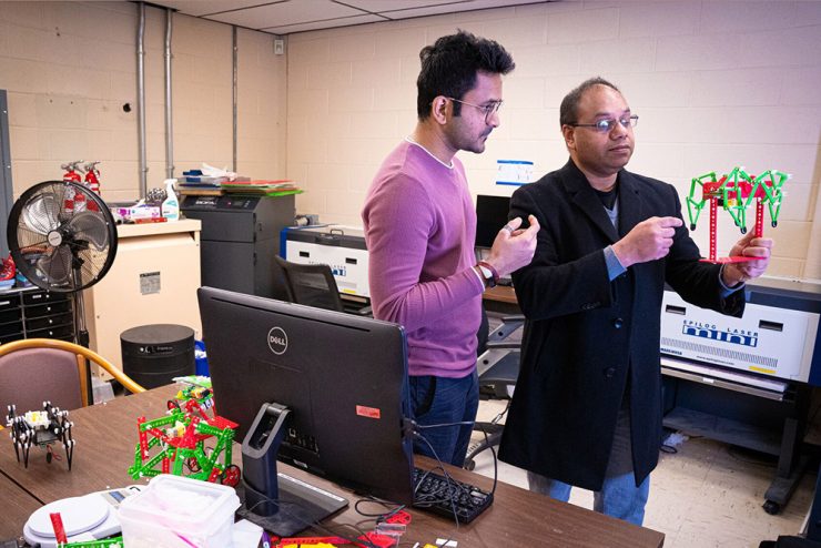 Professor Anurag Purwar shows a robot to a student
