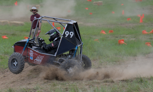 Car #99 kicks up a plume of dust as it races down the course