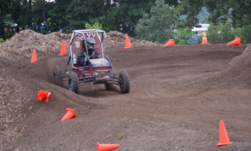 Car #99 is driven around the curve of a dirt course