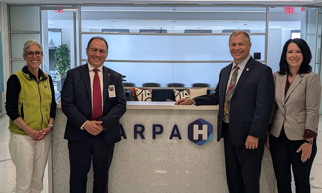 Stony Brook Leaders and Federal Agency leaders pose in front of a desk that says ARPA HQ