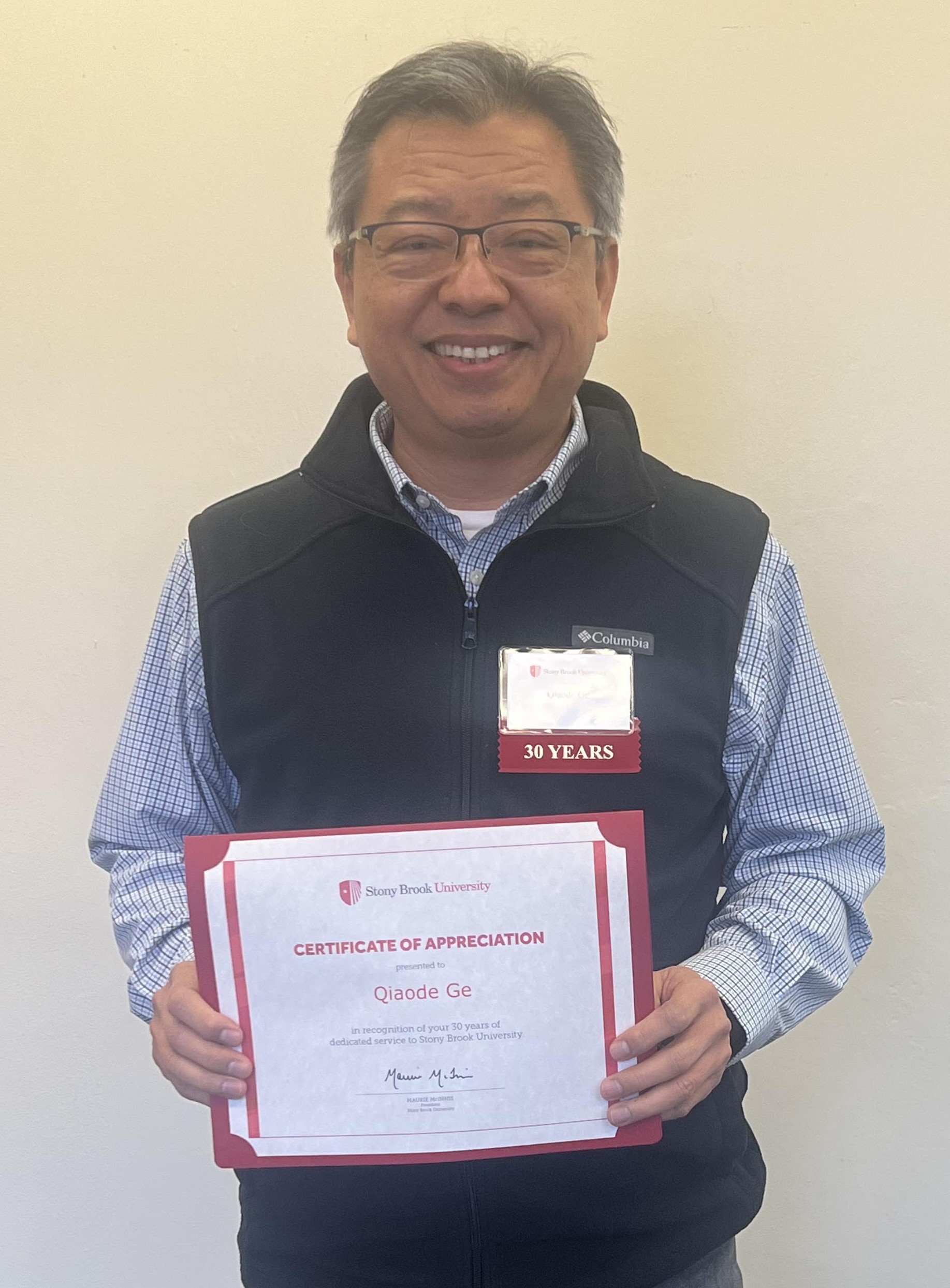 Professor Jeff Ge poses with a certificate honoring his 30 years at Stony Brook University