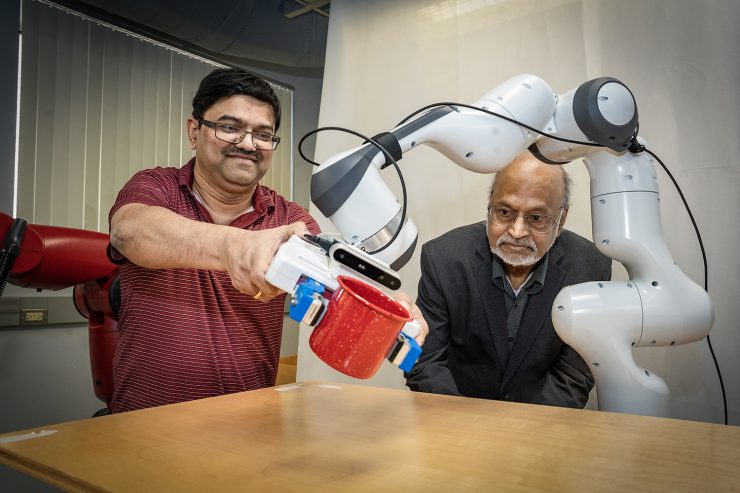Professors work with robotic arm