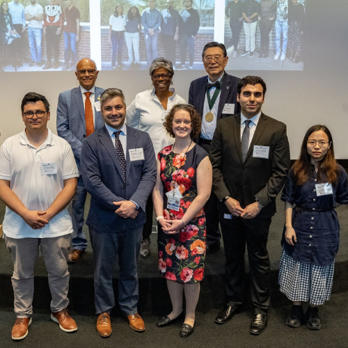 The winners of the Young Academic Inventor Award pose in front of a projector screen