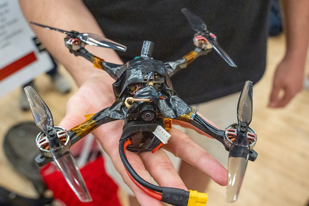 A hand holding an aerial drone with 4 propellers