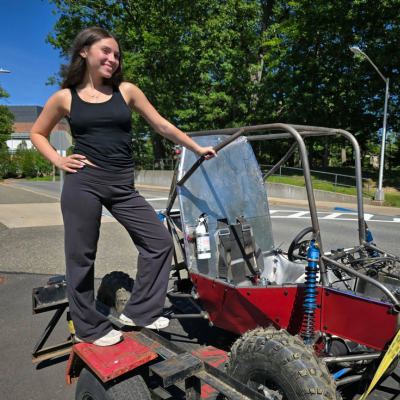 Samantha stands on a red baja style racecar