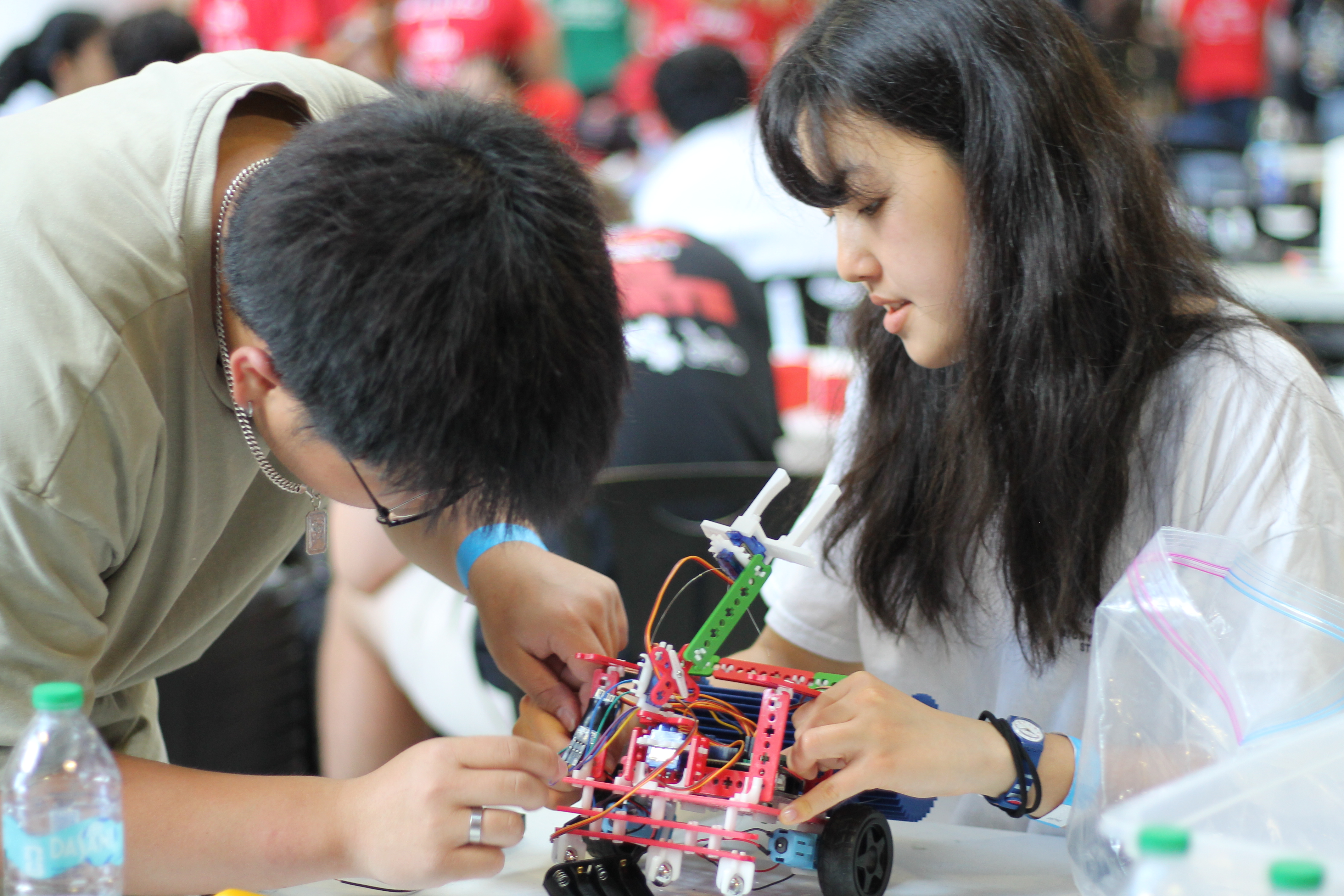 Two students collaborate on assembling and programming a small robotics project during a hands-on engineering activity, demonstrating teamwork, problem-solving, and experiential learning.