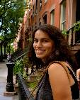 Naomi Vingron, girl in curly hair and smiling in front of apartment houses