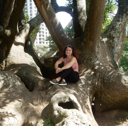 Morgan Macklin; Girl with red hair wearing red and white striped shirt, sitting crossed legged on a tree branch