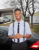 Patrick Gaston; Guy smiling wearing a blue cross-stripped collared shirt and posing in front of a black car
