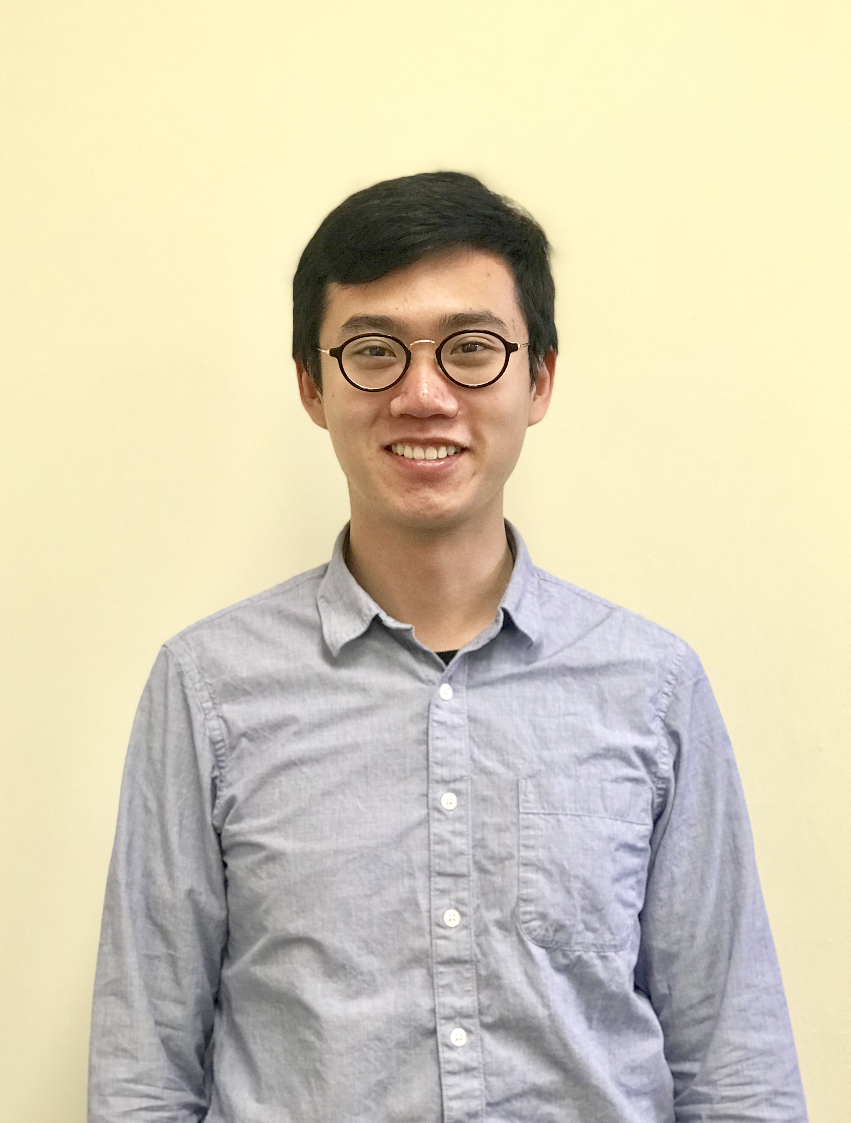 Portrait shot of Hanyu Zhang wearing black round glasses and a blue collared button-down