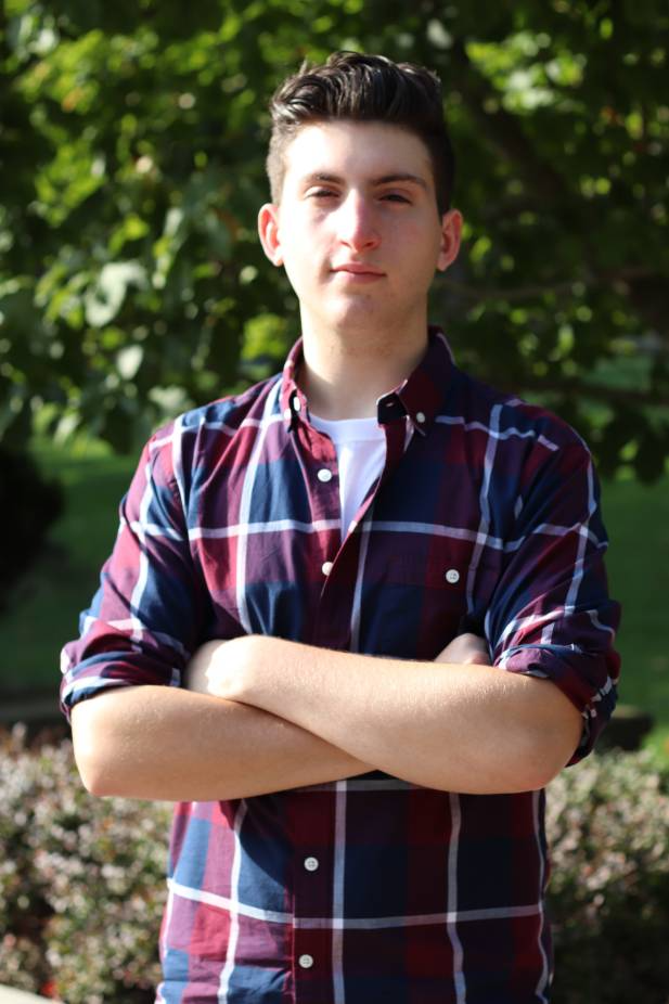 Portrait shot of Joshua Sandground wearing red and blue plaid collared shirt and hands crossed