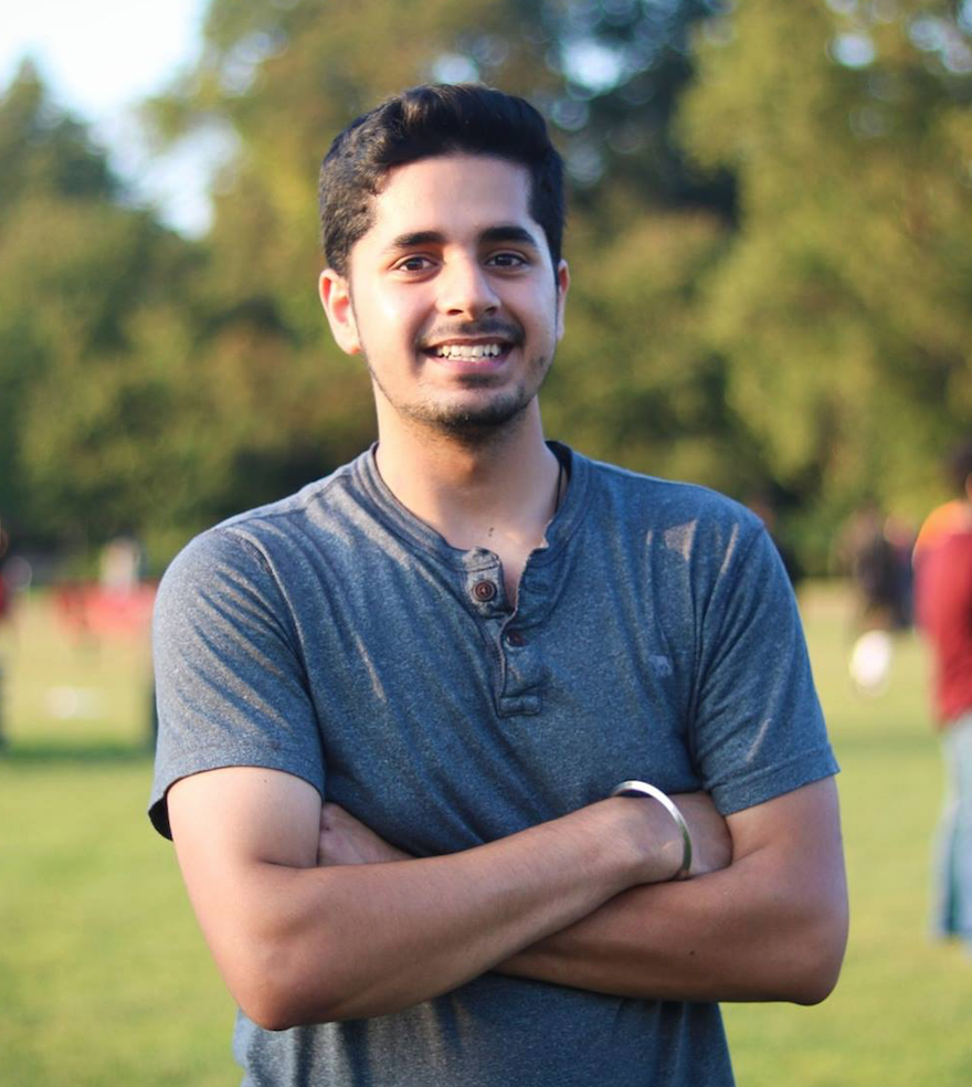 Portrait shot of Rohit Luthra smiling with arms crossed and wearing a gray tee shirt and a sliver bangle bracelet