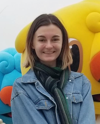 Portrait shot of Claudia Motley with medium length brown hair with blonde streaks wearing a denim jacket and scarf
