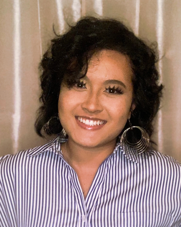 Head shot of Judy Le with black short curly hair and wearing navy and white collared shirt