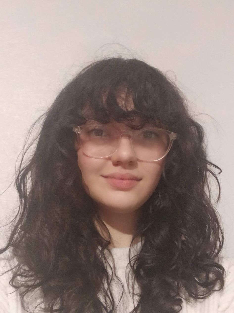 Close up shot of Gabrielle Modeste with curly long hair and pink framed glasses