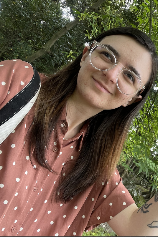 Close-up shot of Melis Tozoglu with long brown hair wearing glasses and pink polka dot shirt