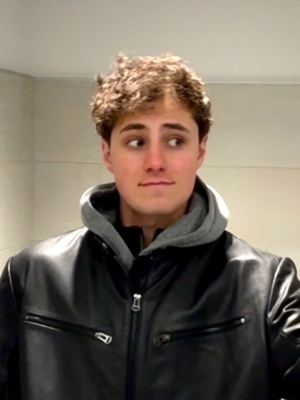 Medium close up shot of Cosmo Perfetti with short blonde hair wearing a winter coat and looking to the side